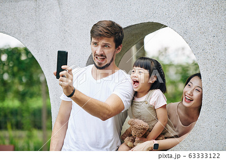 Family taking funny photo in park Family taking funny photo in park 63333122