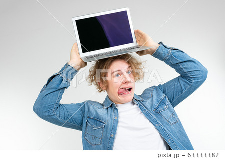 contented cool blond man holding a laptop with a layout for inserting a page on a white background 63333382