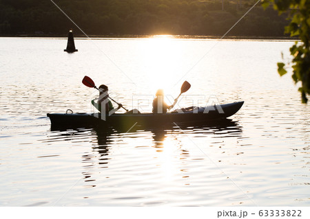 A young couple in kayaks swim on the river. Summer sunny sunset. A young couple in kayaks swim on the river. Summer sunny sunset. 63333822