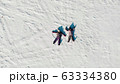 Aerial view from above of children lying on white snow in bright sunshine and making snow angels 63334380