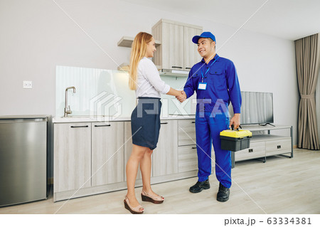 Female customer greeting electrician Female customer greeting electrician 63334381