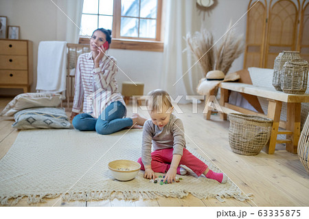 Daughter playing with artificial stones, mom talking on the phone Daughter playing with artificial stones, mom talking on the phone 63335875
