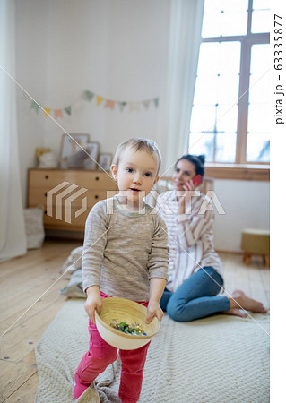 Daughter carrying bowl, mom talking on the phone Daughter carrying bowl, mom talking on the phone 63335877