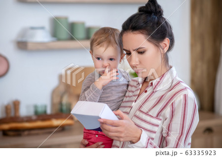 Mom reading medicine instruction, daughter poking nose Mom reading medicine instruction, daughter poking nose 63335923