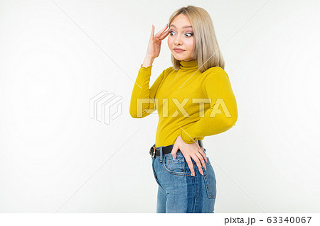 close-up of a girl with a blonde haircut in jeans and a yellow blouse posing on a white isolated 63340067