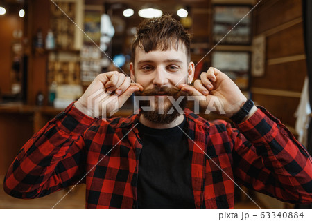 Barber twists his mustache, retro style barbershop 63340884