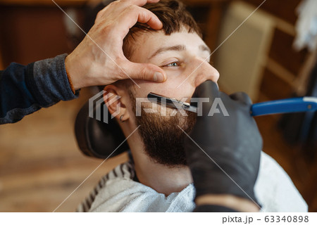 Barber with razor, old school beard cutting 63340898