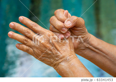 Senior woman's hands washing her hands using soap foam in step 5 on bokeh blue swimming pool Close up shot, Select focus,  Prevention from covid19, Coronavirus, Bacteria, Healthcare, 7 step wash hand Senior woman's hands washing her hands using soap foam in step 5 on bokeh blue swimming pool Close up shot, Select focus,  Prevention from covid19, Coronavirus, Bacteria, Healthcare, 7 step wash hand 63341453