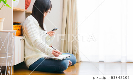スマホとノートを持つ女性 コピースペース 16:9 スマホとノートを持つ女性 コピースペース 16:9 63342102