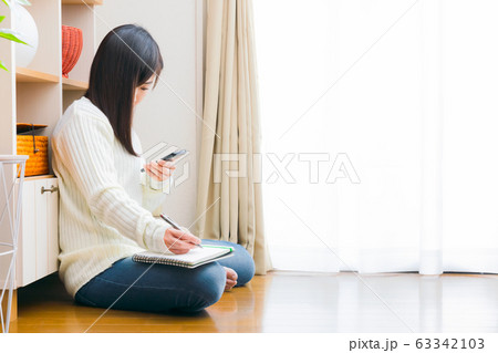 スマホとノートを持つ女性　コピースペース 63342103