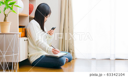 スマホとノートを持つ女性 コピースペース 16:9 スマホとノートを持つ女性 コピースペース 16:9 63342104