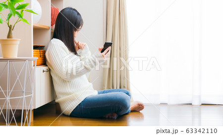 スマホを見て悩む女性　16:9 63342110