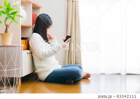 スマホを見て悩む女性 63342111