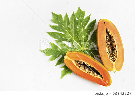 Ripe freshly cut papaya fruit with green leaf Ripe freshly cut papaya fruit with green leaf 63342227