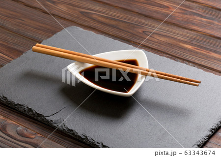 Chopsticks and soy sauce on black stone plate, 63343674
