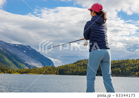 Woman Fishing On Fishing Rod Spinning In Norway Stock Photo