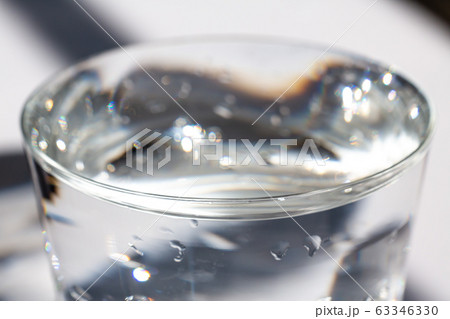 Transparent glass of clean water, Water drops on white background, Bokeh Light & Shadow, Close up & Macro shot, Selective focus, Healthy Drink concept Transparent glass of clean water, Water drops on white background, Bokeh Light & Shadow, Close up & Macro shot, Selective focus, Healthy Drink concept 63346330
