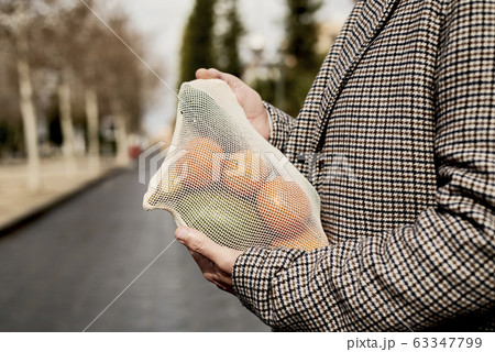 man carrying a mesh bag full of fruit and vegs man carrying a mesh bag full of fruit and vegs 63347799