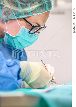 Female surgeon in operation room, operating a patient. Female surgeon in operation room, operating a patient. 63349290