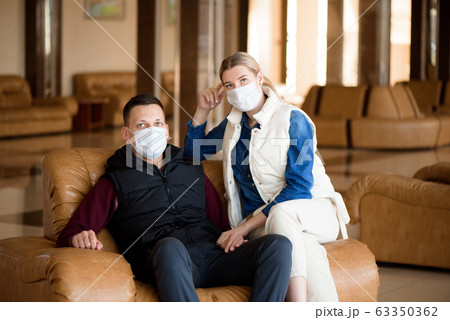Young couple wearing a mask in an airport lounge. Coronavirus influenza virus travel concept. 63350362