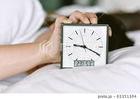 Sleepy girl's hand showing alarm clock and waking up late in the morning Sleepy girl's hand showing alarm clock and waking up late in the morning 63351304
