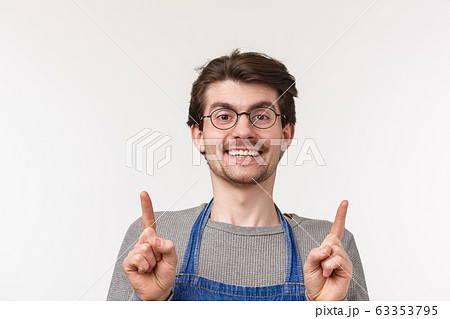 Advertisement, small business and career concept. Close-up portrait of friendly young guy employee working in coffee shop, happy inviting people try best drink in town, pointing up Advertisement, small business and career concept. Close-up portrait of friendly young guy employee working in coffee shop, happy inviting people try best drink in town, pointing up 63353795