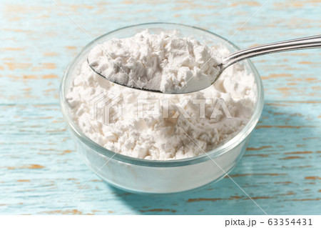 Corn starch in a metal spoon on a on a blue Corn starch in a metal spoon on a on a blue 63354431