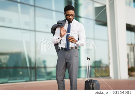 Entrepreneur Using Cellphone Standing With Suitcase At Airport Outdoor 63354983