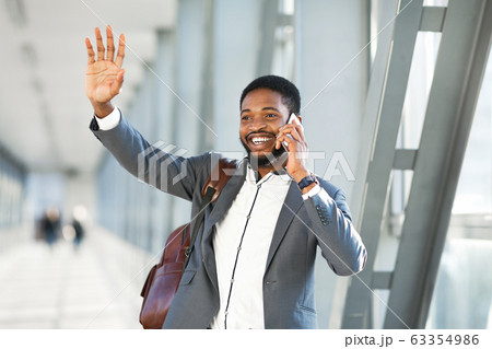 Happy Businessman Waving Hand Talking On Cellphone Walking In Airport 63354986