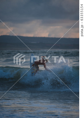 Young people ride on short boards, perform bright tricks on the waves during sunset. Young people ride on short boards, perform bright tricks on the waves during sunset. 63355154
