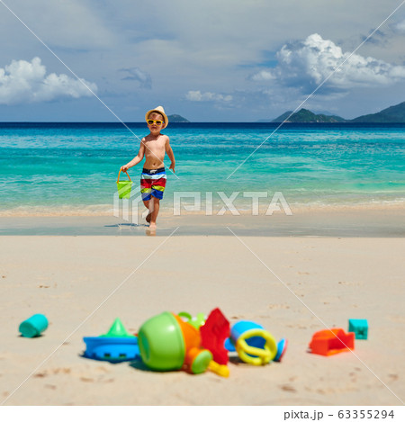 Three year old toddler playing on beach Three year old toddler playing on beach 63355294