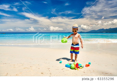 Three year old toddler playing on beach Three year old toddler playing on beach 63355296
