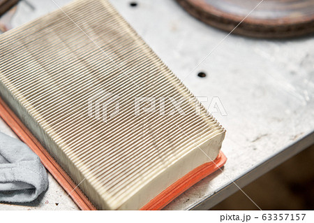 Old dirty automotive engine air filter on metal table of an auto mechanic. Auto repair concept. Old dirty automotive engine air filter on metal table of an auto mechanic. Auto repair concept. 63357157