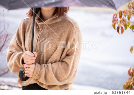 女性が雨の中傘を持っている 63361344