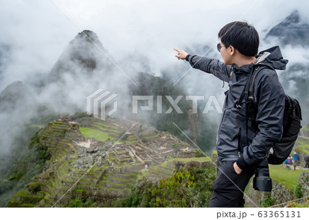 Young Asian man traveler pointing at Machu Picchu 63365131