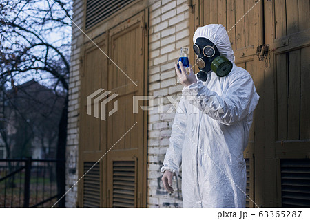 Scientist doing research outdoors, wearing white coverall and gas mask 63365287