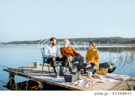 Man and woman with senior grandfather on the picnic outdoors 63368645