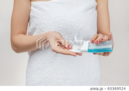 close-up woman in towel holding cotton pad and makeup remover 63369524