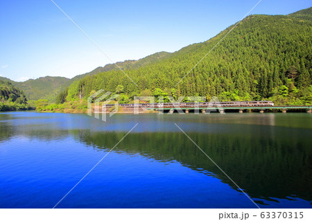 ダム湖畔を静かに走りゆくワイドビューひだ号 63370315