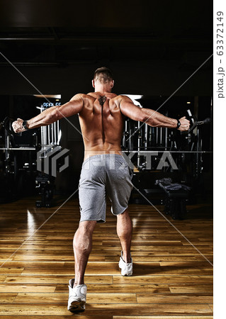 A man trains his chest in a simulator in the gym, makes a hand layout. , powerlifting, fitness. Low key, copy space. A man trains his chest in a simulator in the gym, makes a hand layout. , powerlifting, fitness. Low key, copy space. 63372149