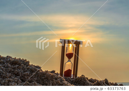 Time concept Hourglass on sandy beach in summer with sea background. Time concept Hourglass on sandy beach in summer with sea background. 63373763