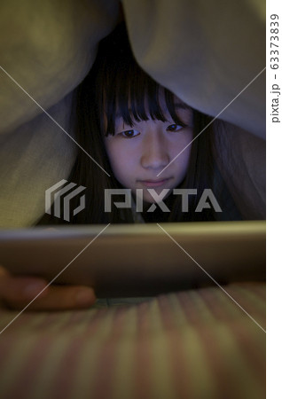 布団の中でタブレットPCを見る子ども 63373839