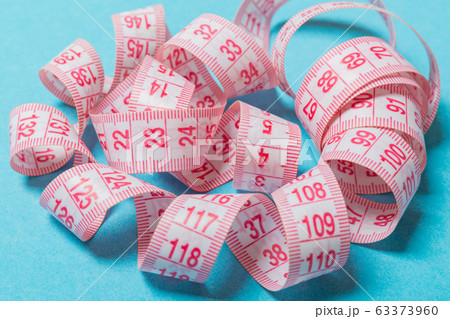 Close up of tangled measuring tape on blue Close up of tangled measuring tape on blue 63373960