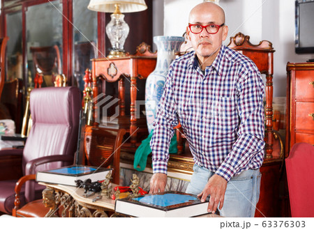 Man choosing books in antique store 63376303