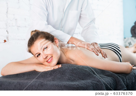 Woman massage therapist massaging relaxing young woman Woman massage therapist massaging relaxing young woman 63376370