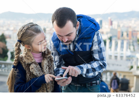 Father and daughter looking at guide in phone Father and daughter looking at guide in phone 63376452