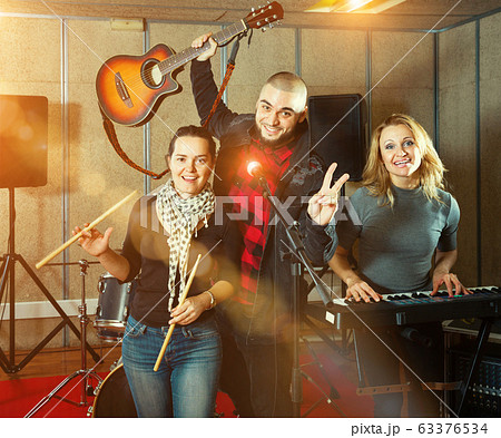 Three bandmates posing together with musical instruments in rehe 63376534