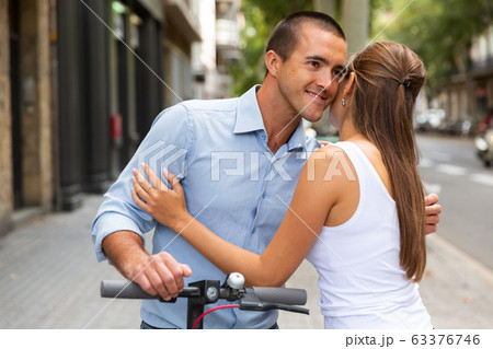 Couple hugging during riding together kick scooter in city center Couple hugging during riding together kick scooter in city center 63376746