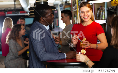 Couple of cheerful smiling male and female on party in the club with cocktails Couple of cheerful smiling male and female on party in the club with cocktails 63376749