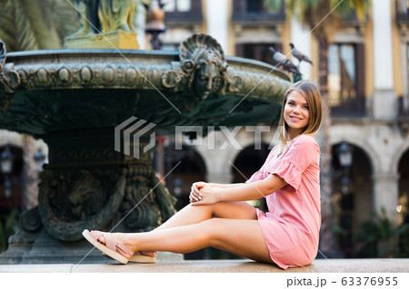 Sexy woman tourist in dress sitting at stone bench near fountain Sexy woman tourist in dress sitting at stone bench near fountain 63376955